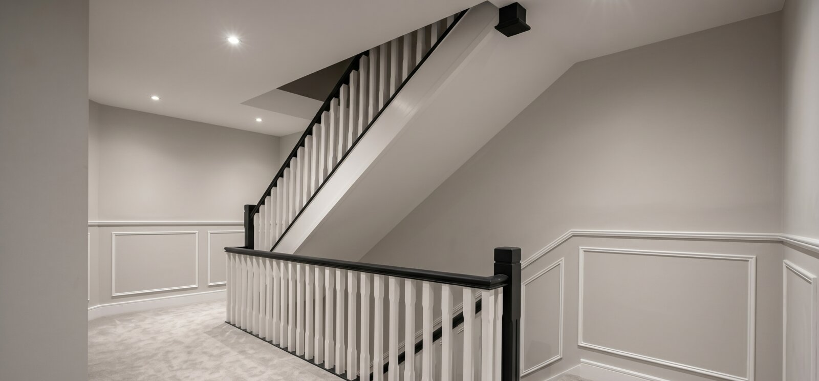 Freshly painted Dublin staircase and landing with white balustrade, black handrail, and panelled walls